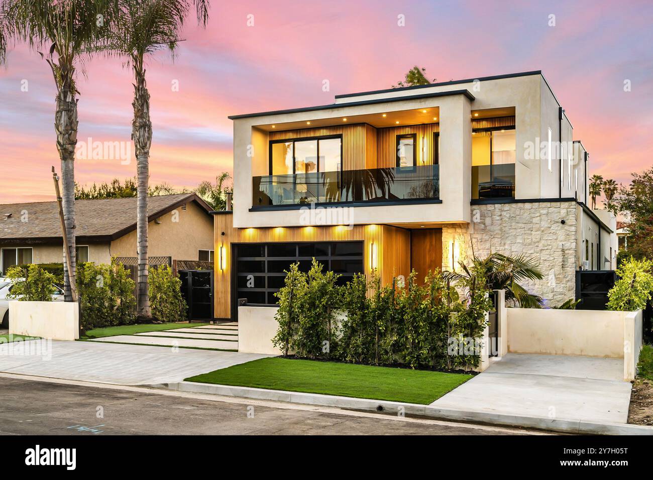 Modern luxury home exterior with palm trees and a beautiful sunset sky ...