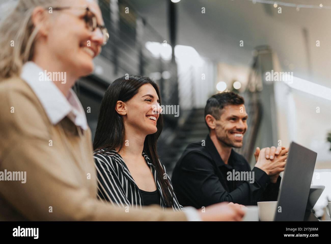 Happy young female business professional with colleagues working at office Stock Photo