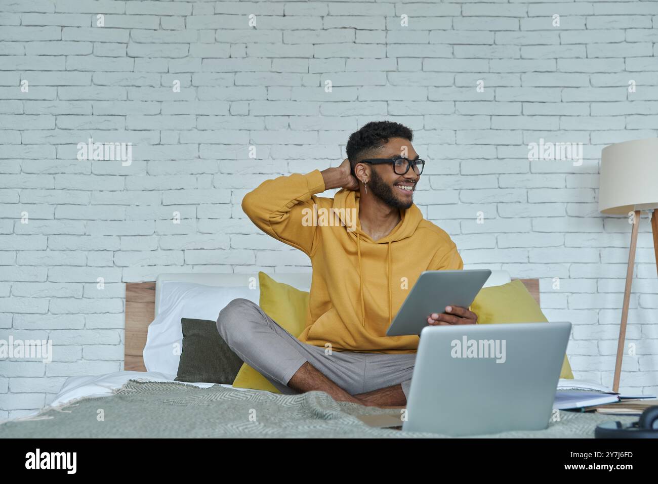 Happy African man using technologies while sitting on the bed at home Stock Photo