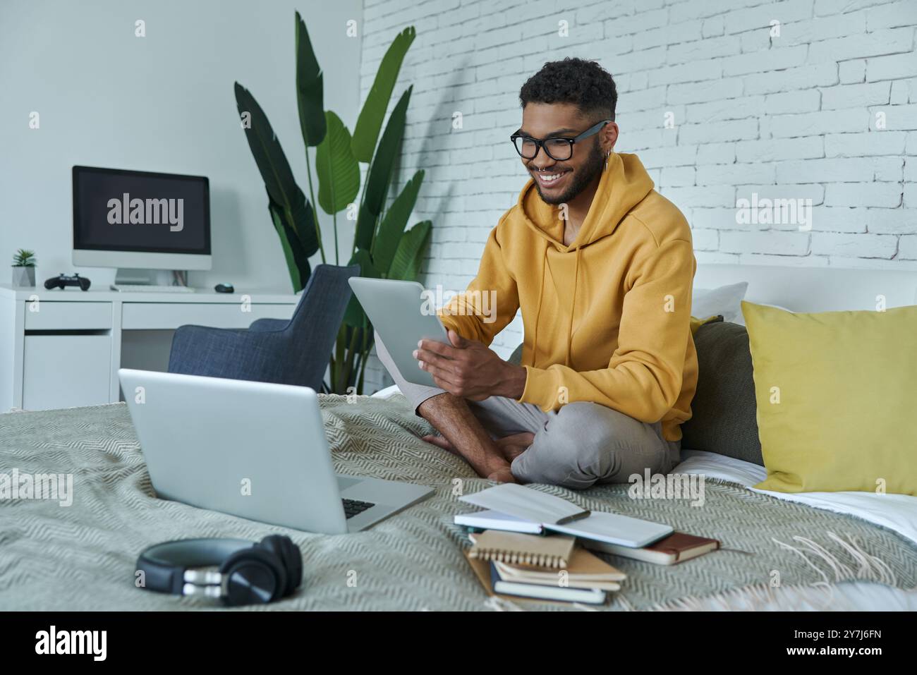 Happy African man using technologies while sitting on the bed at home Stock Photo