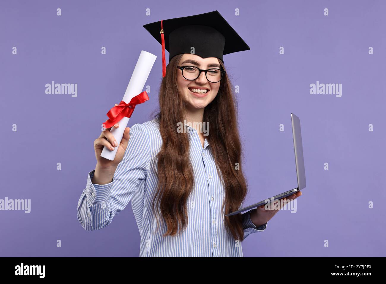 Happy student with laptop and diploma after graduation on violet ...