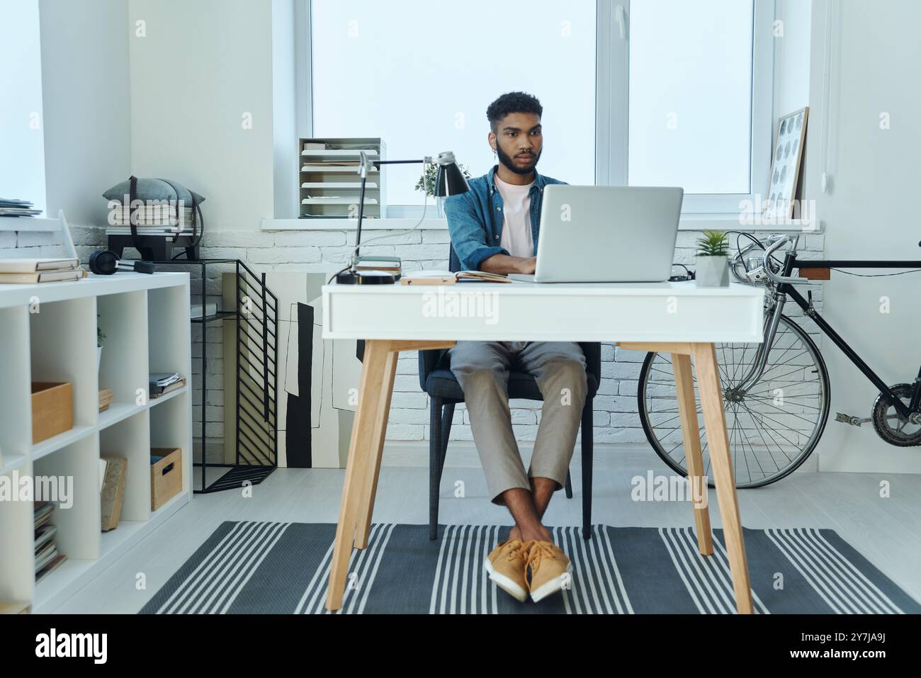 Concentrated young African man using laptop while working in office Stock Photo