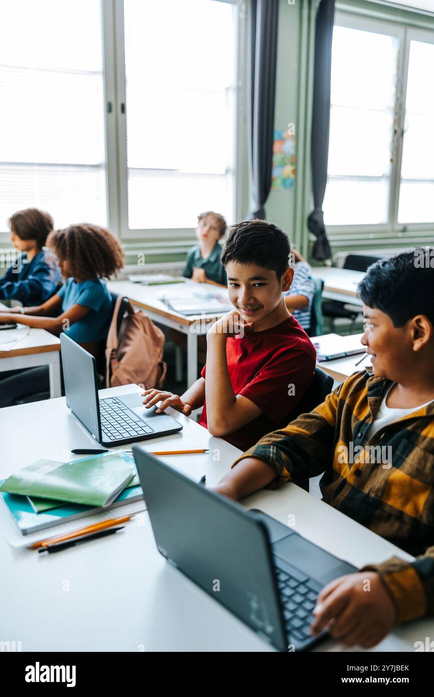 Schoolboys studying on laptop while sitting in classroom at elementary school Stock Photo