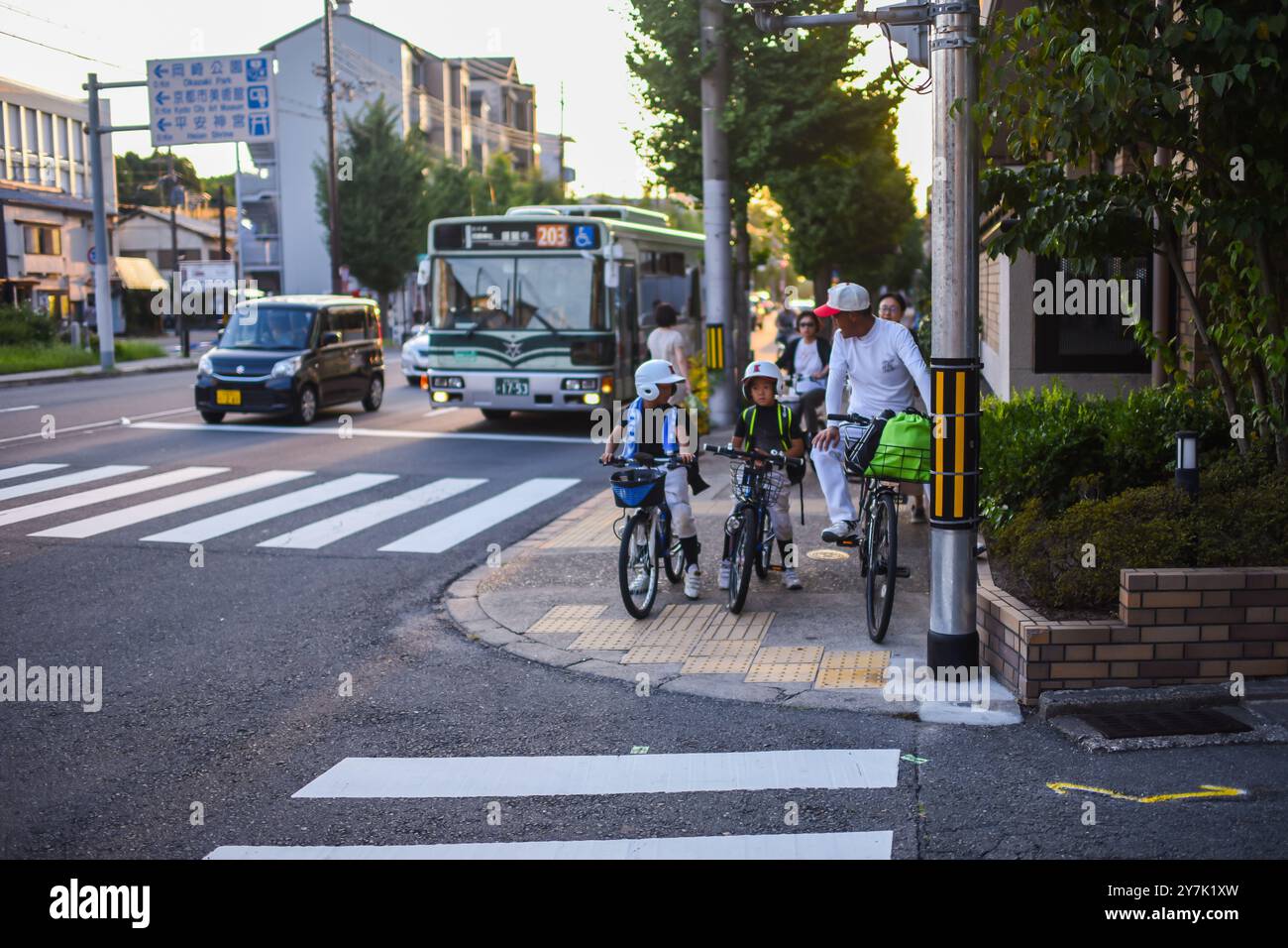 Kids on bikes waiting to cross a street of Kyoto, Japan Stock Photo