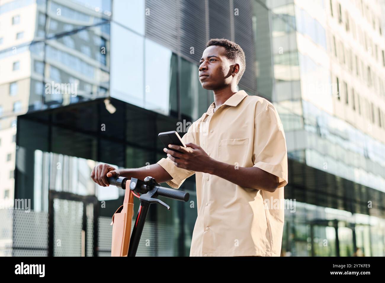 Young Man Standing With E-scooter Outdoors Stock Photo