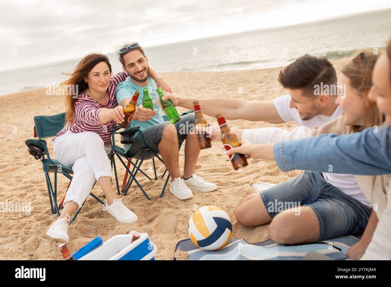 Friends enjoying drinks together on the beach during a sunny day Stock ...