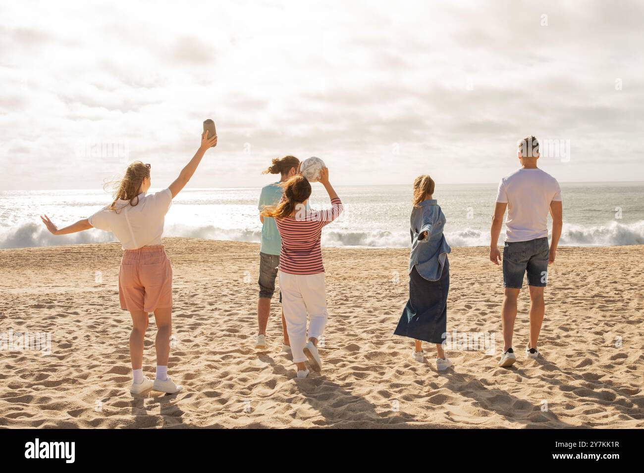 Friends enjoying a sunny beach day while playing with a volleyball by ...