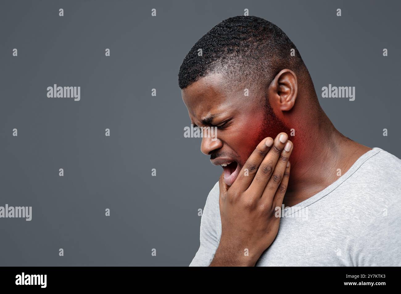 Young man having acute toothache, holding his jaw Stock Photo