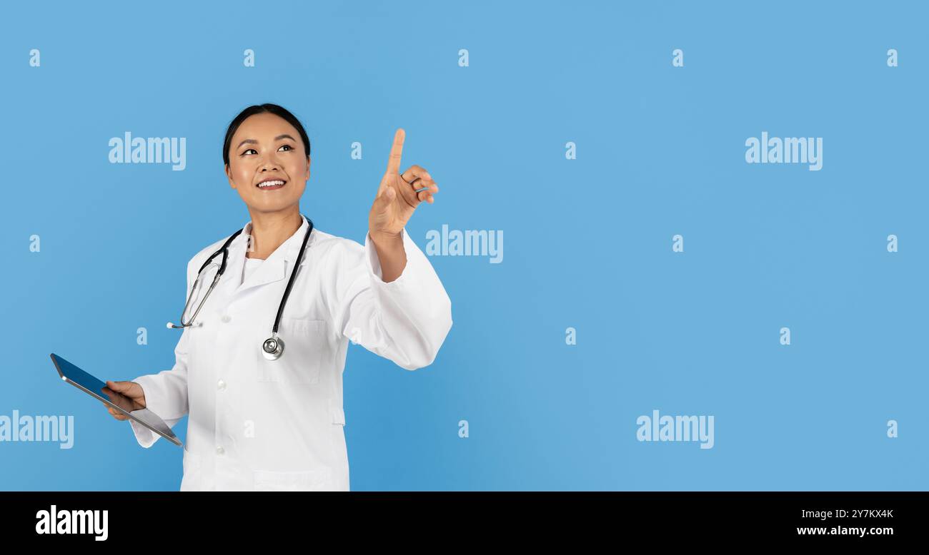 Doctor in a white coat explaining concepts on a blue backdrop Stock Photo