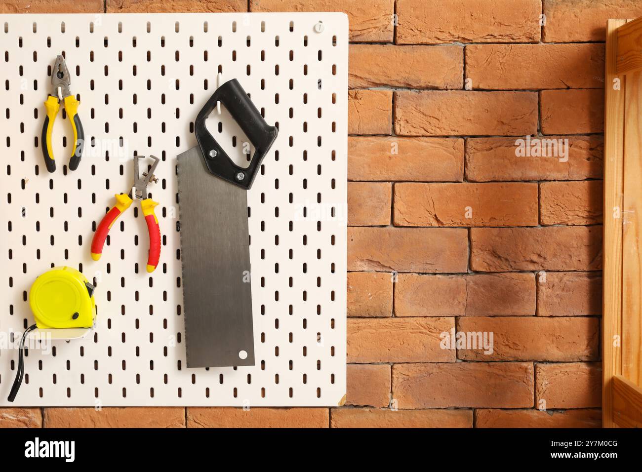 Pegboard with builder's tools on brick wall in workshop Stock Photo