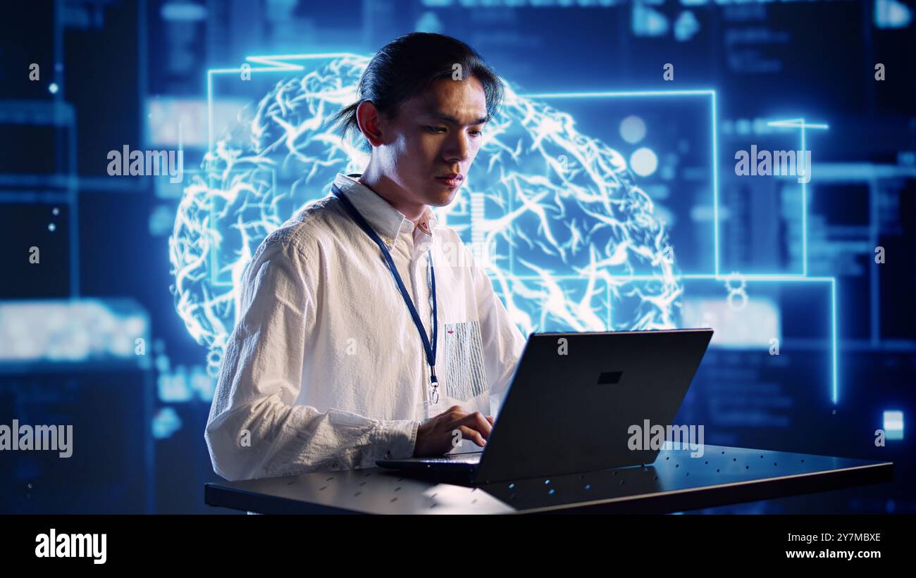 Efficient engineer in cloud computing company uses artificial intelligence computing simulating human brain. Focused admin running operations on laptop with AI machine learning algorithms Stock Photo
