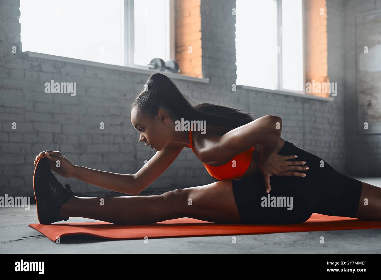 Concentrated young African woman stretching on splits in gym Stock ...