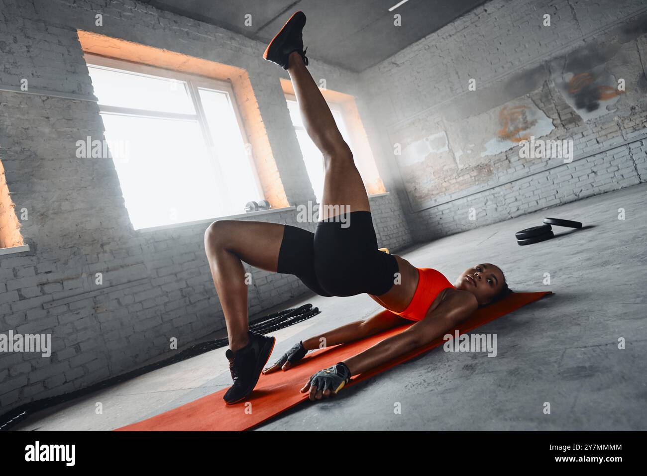 Beautiful young African woman doing stretching exercises while lying on ...