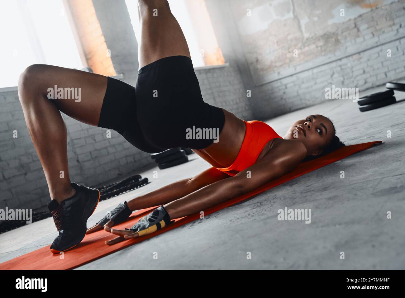 Confident young African woman doing stretching exercises while lying on ...