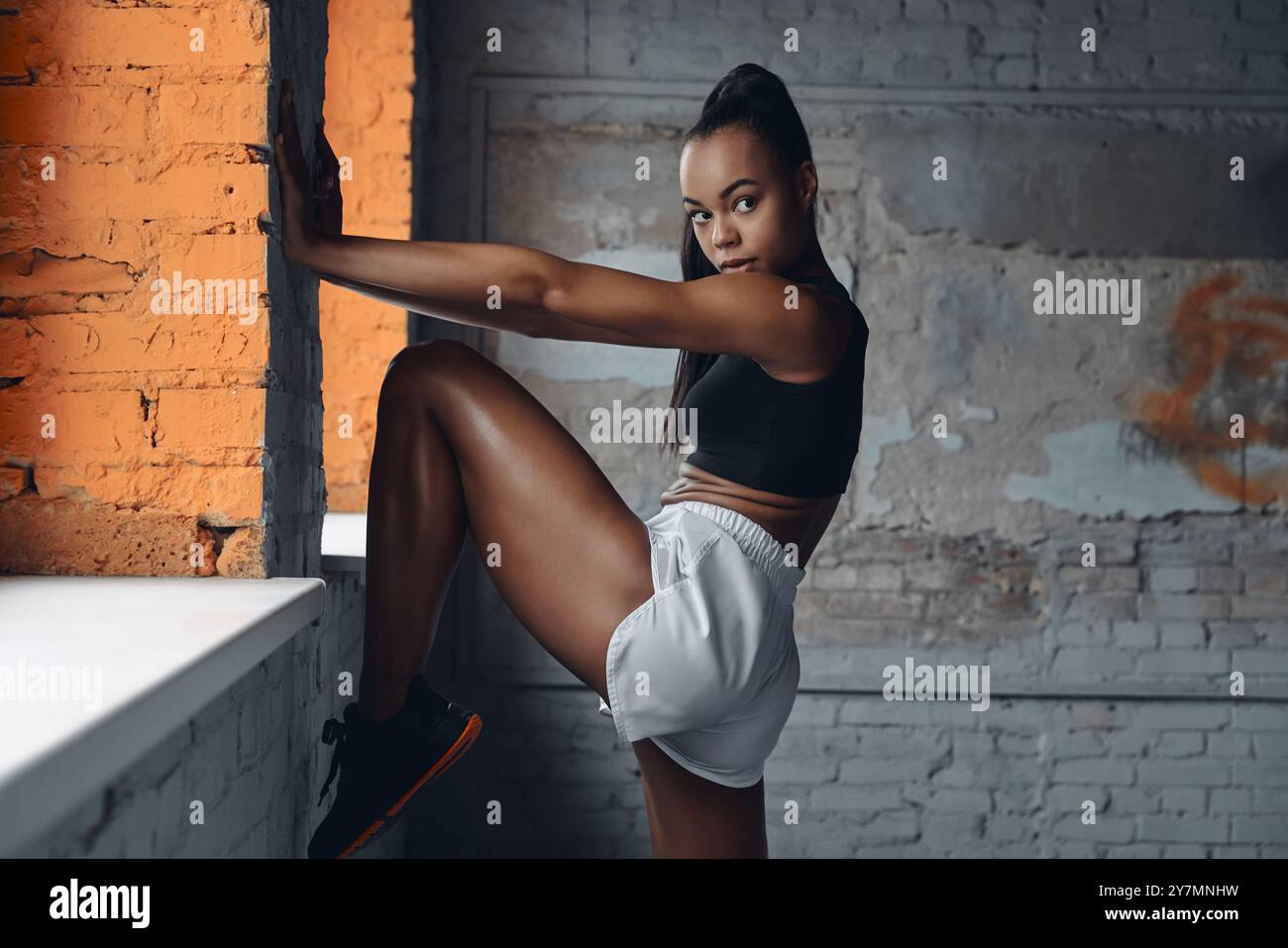 Confident African woman in sports clothing doing stretching exercises ...