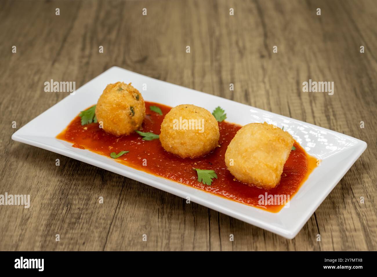 Crispy breaded Italian rice balls served over spicy red sauce as an ...