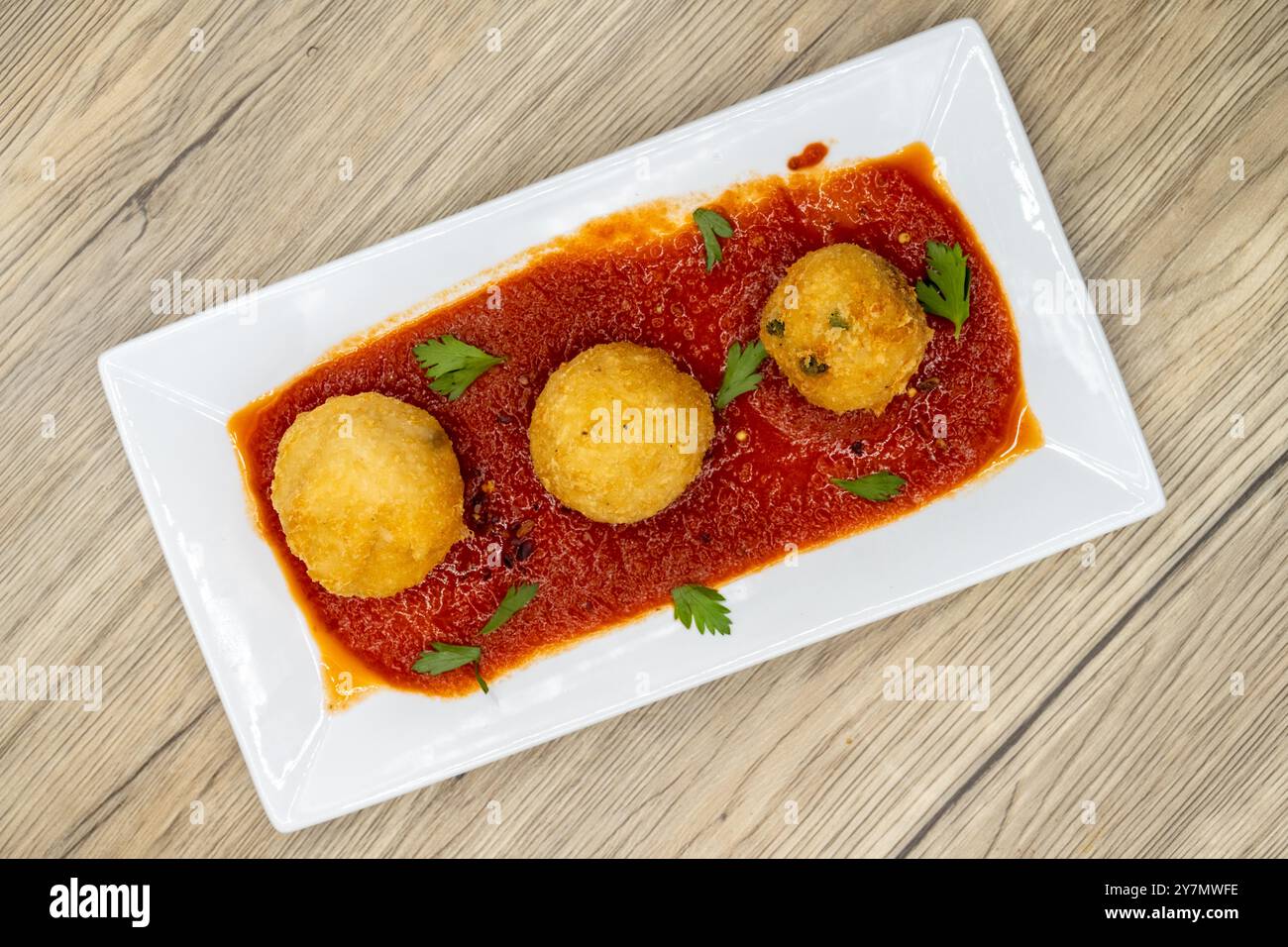 Overhead view of crispy breaded Italian rice balls served over spicy ...