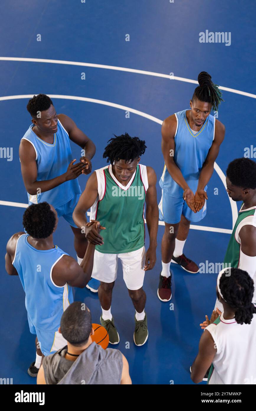 African American basketball players in team huddle on court, discussing game strategy together Stock Photo