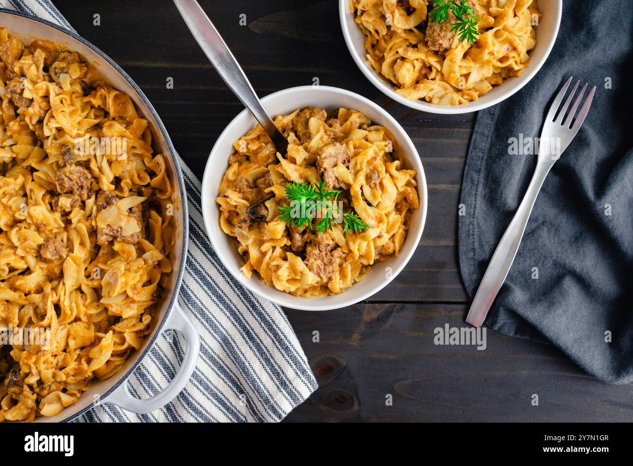 Bowls of Beef Stroganoff Garnished with Parsley: Cube steak and egg noodles in mushroom-sour cream sauce cooked in a large cast-iron braising pan Stock Photo