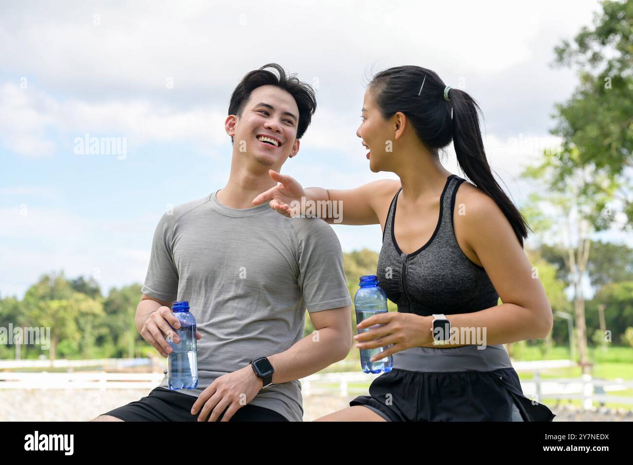 A happy, healthy Asian couple in sportswear enjoys chatting while ...