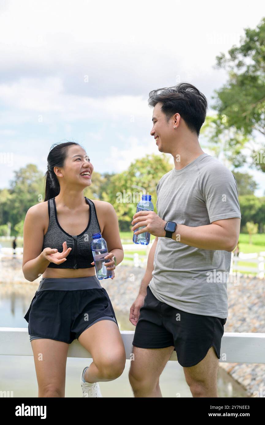A happy, healthy Asian couple in sportswear enjoys chatting while ...
