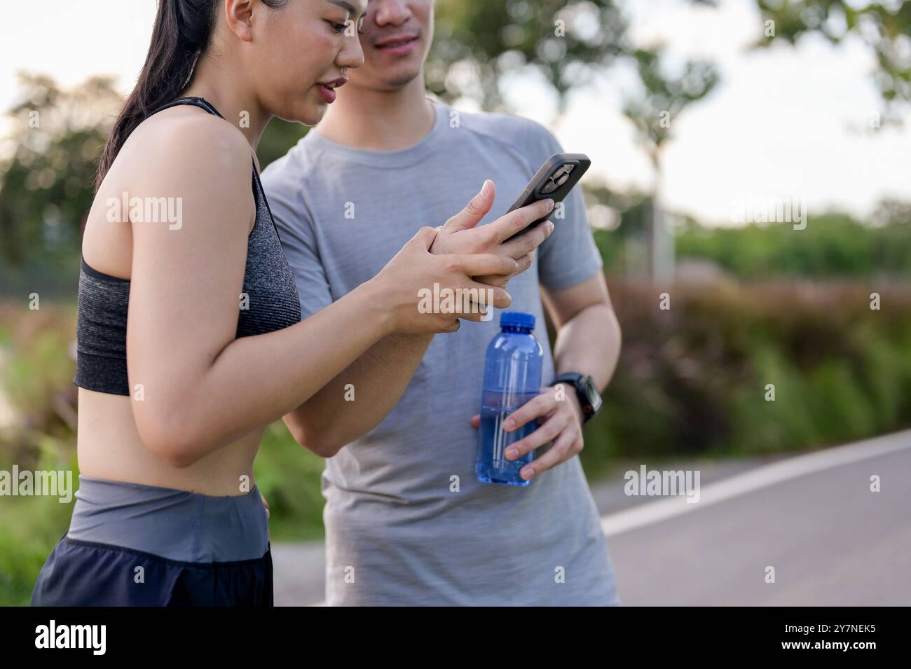 A cropped image of a sporty Asian couple in sportswear is looking at ...