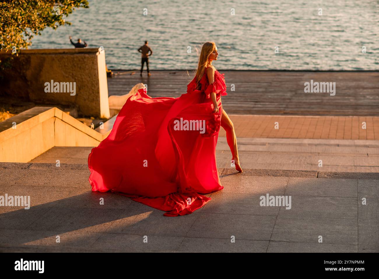 Sunrise red dress. A woman in a long red dress against the backdrop of ...