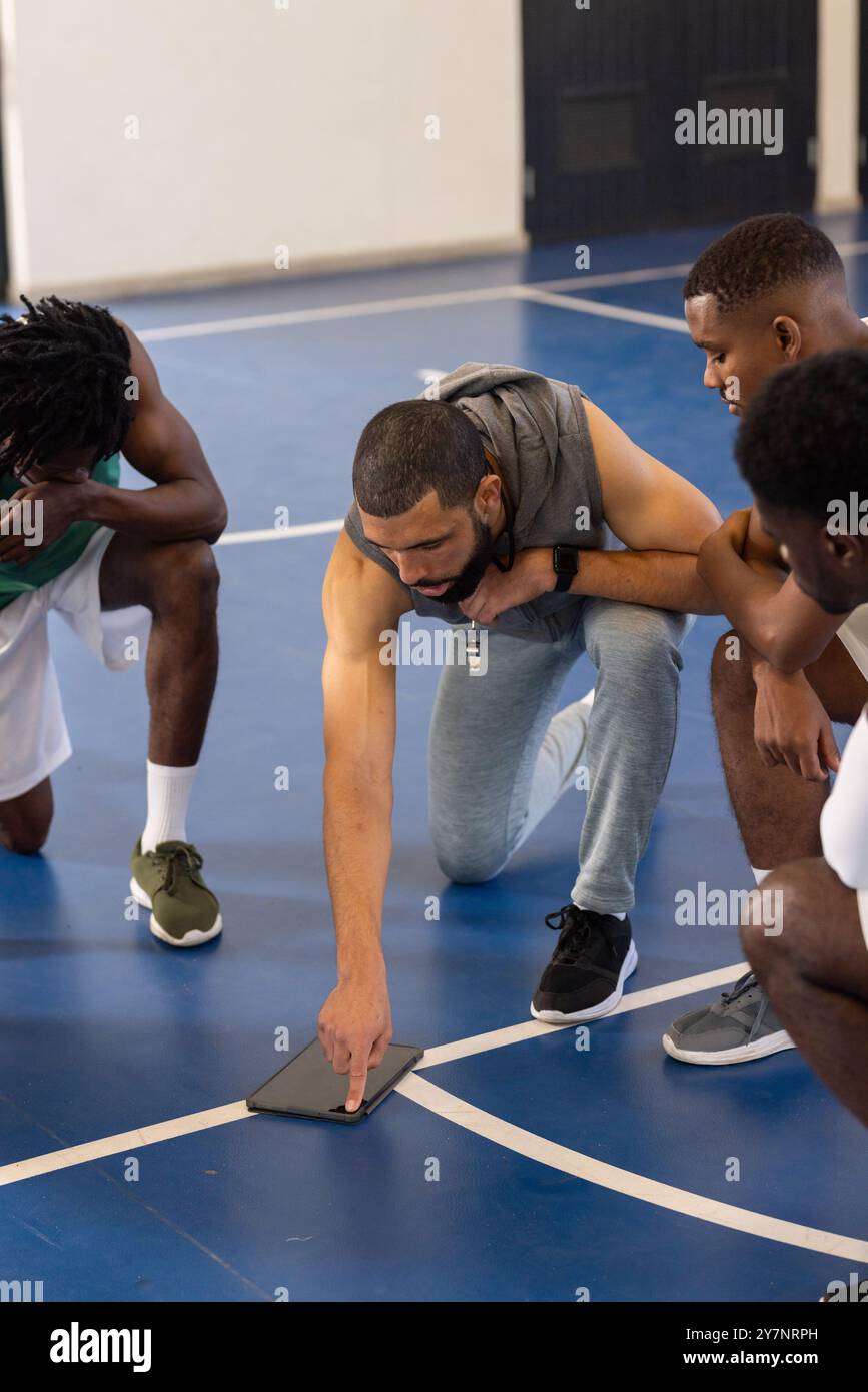 Basketball coach using tablet to discuss strategy with players on court Stock Photo