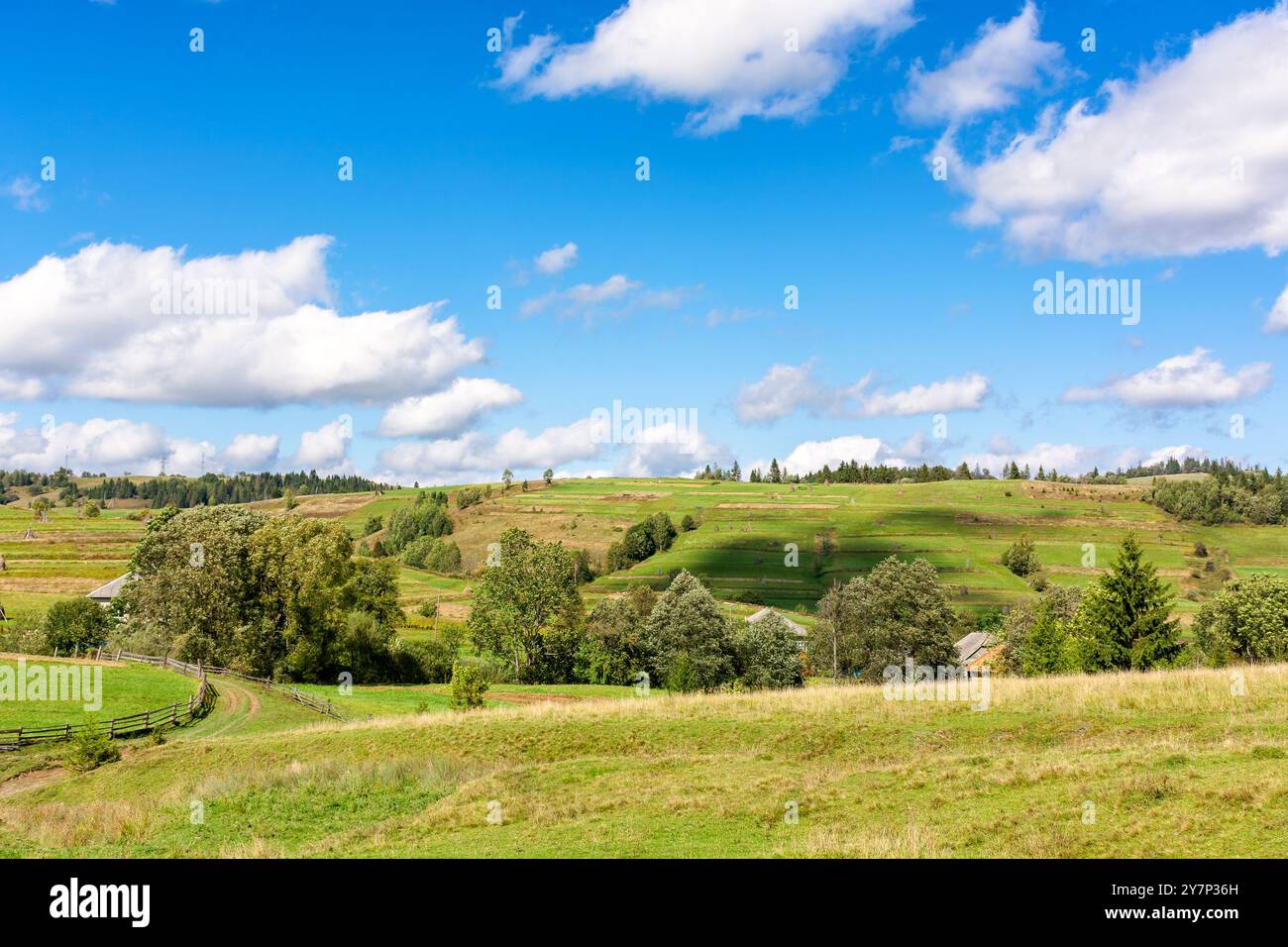 rural valley with village behind the field. early autumn green ...