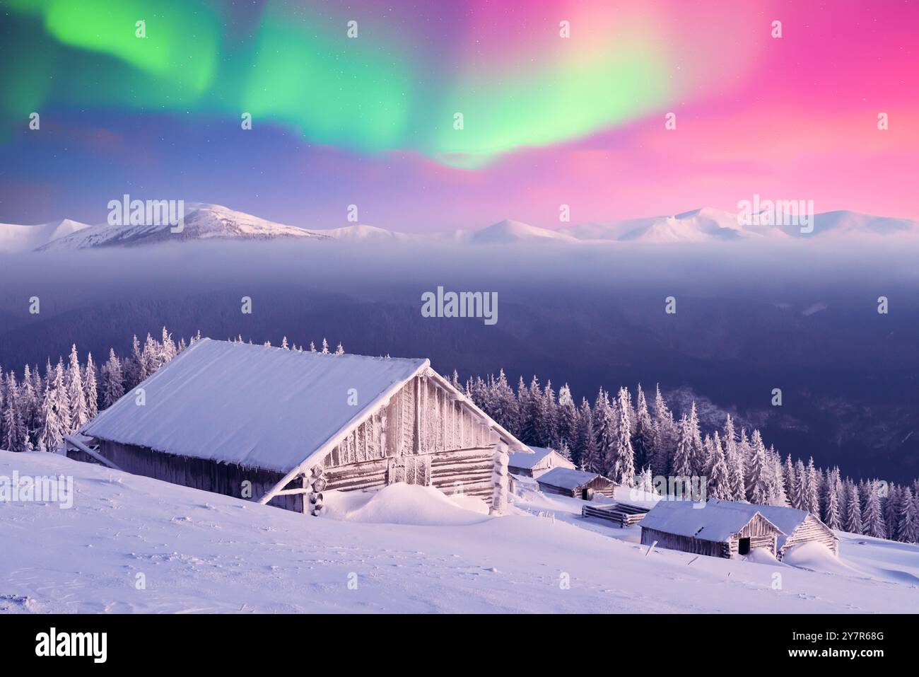Old wooden cabins in snowy mountains under incredible Northern lights ...