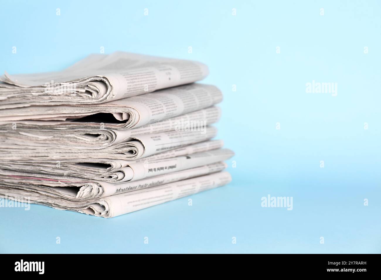 Stack of newspapers on light blue background, space for text Stock Photo