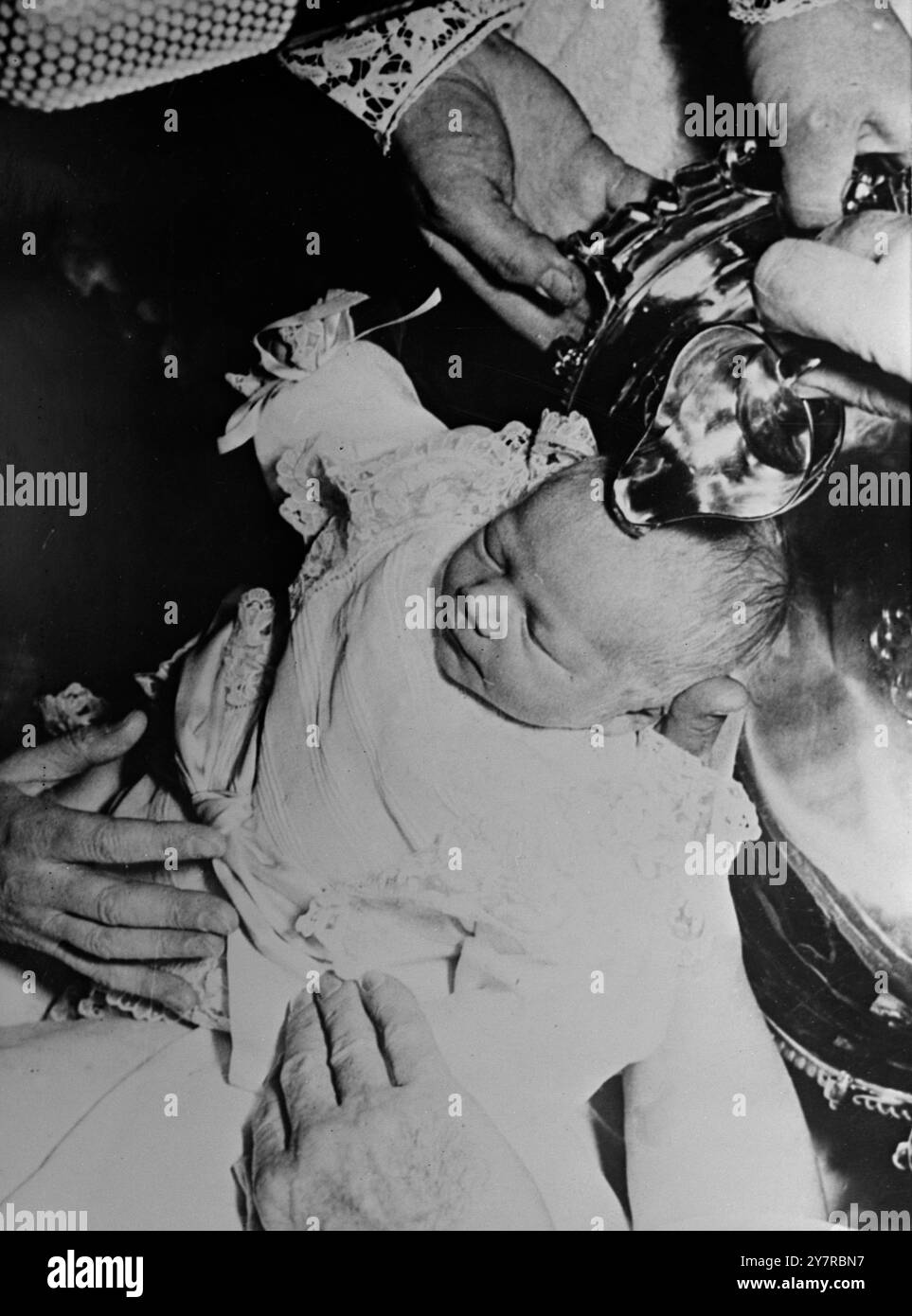 THE PRINCESS OF LUXEMBURG CHRISTENED 22.254. The five-day-old daughter of Prince Jean and Princess Josephine of Luxemburg was christened on Saturday. At the baptismal ceremony in Prince Jean's Betzdorf Palace she was named: Marie Astrid, Charlotte Leopoldine Wilhelmine, Ingeborg Antonia Elsa Elizabeth, Anna. Her godfather was ex-King Leopold III of Belgium who is her grandfather. I.N.P. photo shows - the tiny princess closes her eyes as the bishop holds the holy water over her head ready to pour. 494/MB/74706 International News Photos. Stock Photo