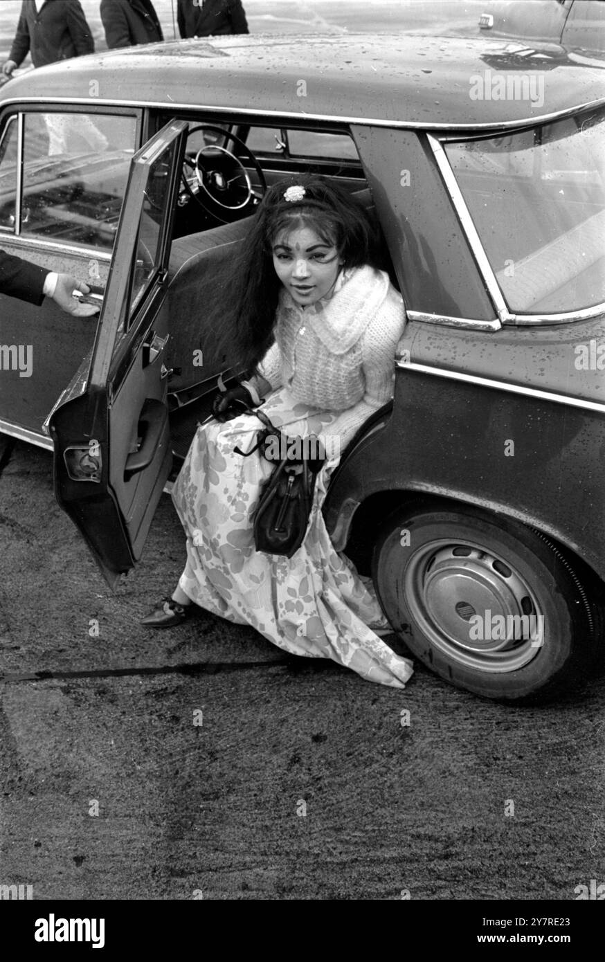 PEERLESS BELLY DANCER TO MAKE MOVIELondon Airport, England, UK : Lady Moynihan, the belly dancer is shown on her arrival at London Airport from Tripoli today. Her father-in-law, the late Lord Moynihan was a former chairman of the Liberal Party. Known previously as Princess Amina, she was born Shirin Berry in Malaya. Lady Moynihan is renowned for her belly dancing skill in night spots throughout the world. In March she is due to appear at the Pigalle nightclub, London, and is beginning a new career as a film star in a £500,000 production called 'Whoosh !' She has the leading role - a girl from Stock Photo