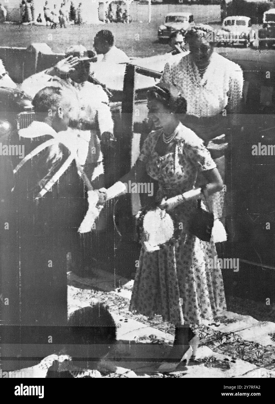 Radio from Suva. Queen goes to church in Tonga. Queen Elizabeth is greeted by a minister of the Wesleyan Church in Tonga upon her arrival there to attend morning service today, December 20th. Stepping out of the car behind her is Queen Salote of Tonga, who accompanied the Queen and her husband, the Duke of Edinburgh, to the service. The Duke read the first text of the service to the crowd of over 3,000 Tongans in the church. The Queen and the Duke are visiting this Pacific island as part of their current round-the-world tour of the Commonwealth. POOL/gd/ap/73394a. International news photos. Stock Photo