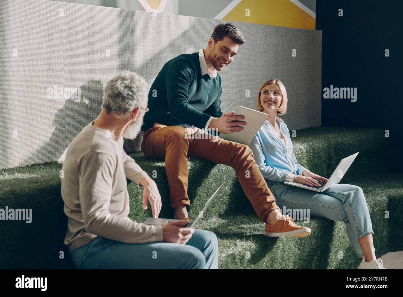 Confident business people talking and using technologies while working in creative office Stock Photo