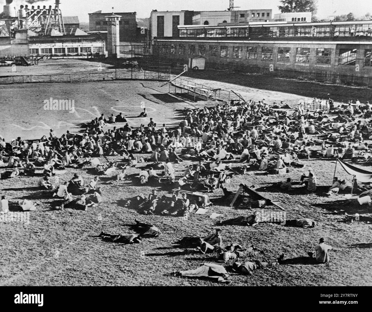 CONVICT RIOTERS COOLED OFF 14.7.53Rebellions convicts at Oregon State Prison were driven to the Ball Diamond after rioting and setting fires. About 800 were involved in the rebellion. Hungary and thirsty after spending the night without food and water the rioters offered to capitulate. Warden Clarence T Gladden told them they would be returned to their cells provided they obeyed prison rules. Photo shows - The prisoners bedding down for the night in the recreation field. 14 July 1953 Stock Photo