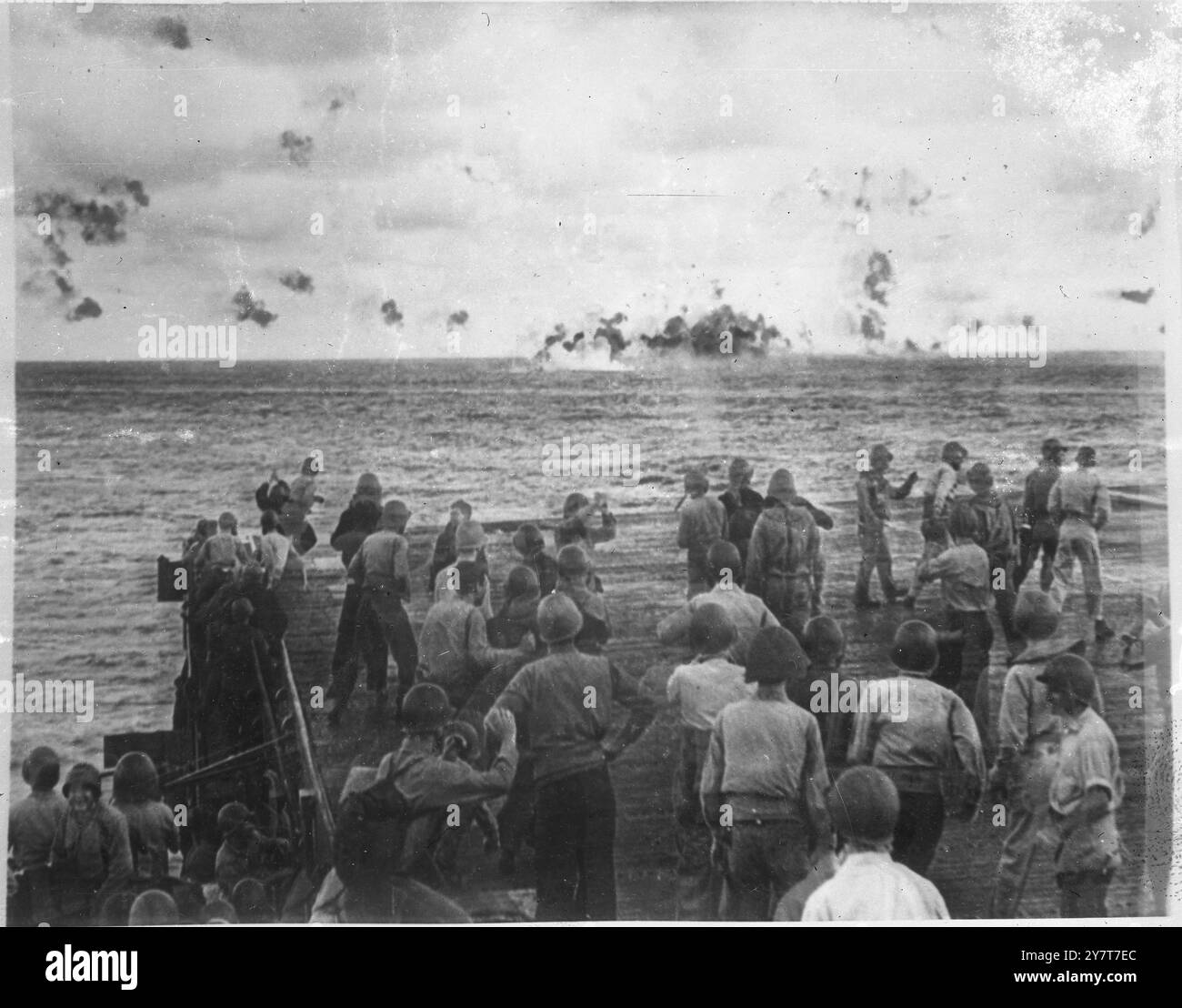 DEATH OF A JAPANESE TORPEDO BOMBER 1944 PHOTO SHOWS:- 2. He’s down! The crew of the Pacific Fleet light carrier cheer and congratulate the gunners as the Japanese torpedo bomber hits the sea and explodes. Black flack-puffs trace the course of the plane. 2 June 1944 Stock Photo