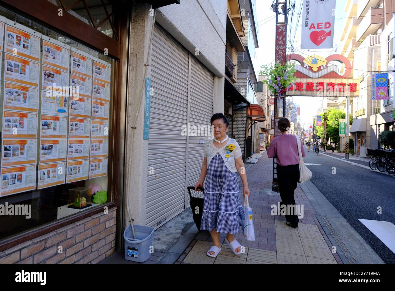 An elderly shopper on Sugamo Jizou-dori Shopping Street with the street gate in the background.Toshima City.Tokyo,Japan Stock Photo