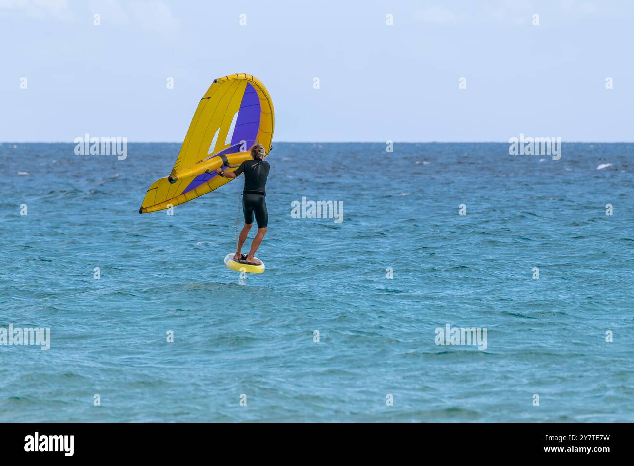 A wing foiler takes advantage of the strong wind blowing on the sea of Santa Margherita di Pula, Sardinia, Italy Stock Photo