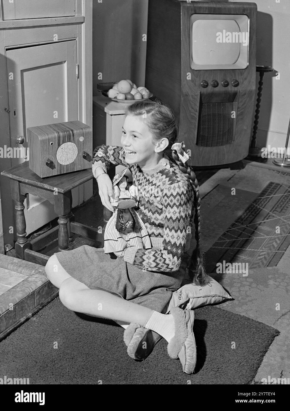 STAR OF ELEVEN  Girl with a charming smile is 11-year-old Janette Scott, star of the film ' No Place for Jennifer ', shown here holding her favourite French doll, ' Janine ' and listening to a programme on her midget wireless set at home in Leicester Mews, Lancaster gate, London. The wireless set is the cheapest mains set in Europe and sells for £6/19/9d . including purchase tax. 12 February 1950 Stock Photo