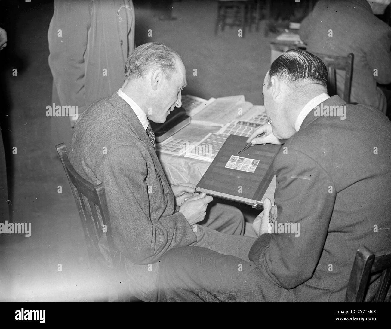 Hitler downfall stamps at International Bourse in LondonDealers from many countries are attending the International Stamp Trade Bourse which has opened at the Central Hall , Westminster .  Photo shows: Mr L Klein of Austria ( left) and Mr C Taylor of Britain examinng a special set of stamps issued in Austria recently to commemorate the downfall of Hitler 30 September 1946 Stock Photo