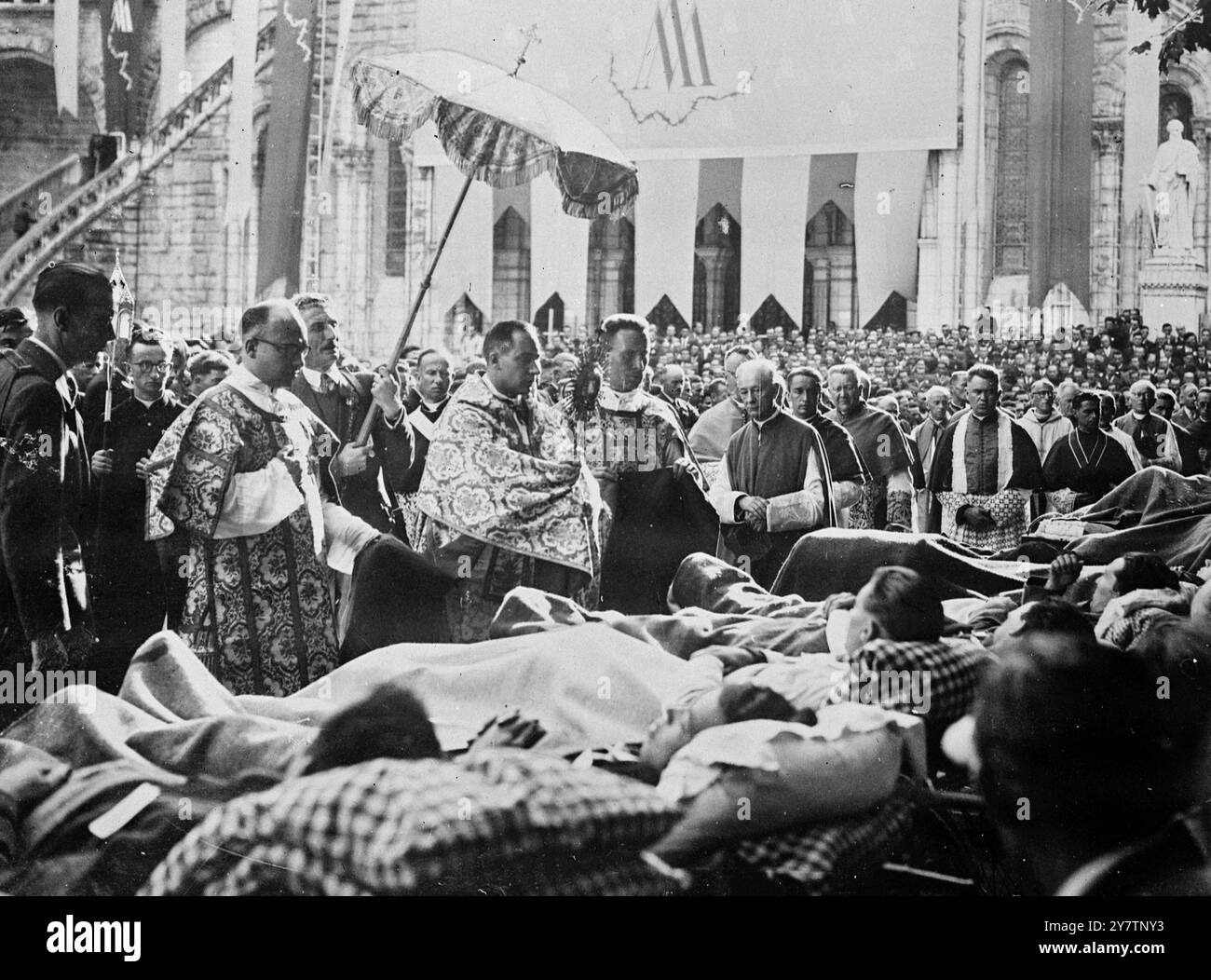 EX WAR PRISONERS PILGRIMAGE TO LOURDES In a great demonstration of faith anf thanksgiving for deliverance, hundreds of former prosoners of war and deportees, many of them disabbled, took part in a pilgrimage to Lourdes, France. Photo Shows: Disabled ex prisoners seated in invalid chairs before the Grotto. 1946 Stock Photo