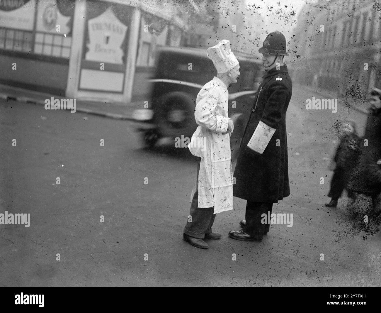 A STUDY IN BLACK AND WHITE Photo Shows: The chef of the New Zealand Services Club in London pauses for a question to the policeman on point duty in a London Street.  19 January 1942 Stock Photo