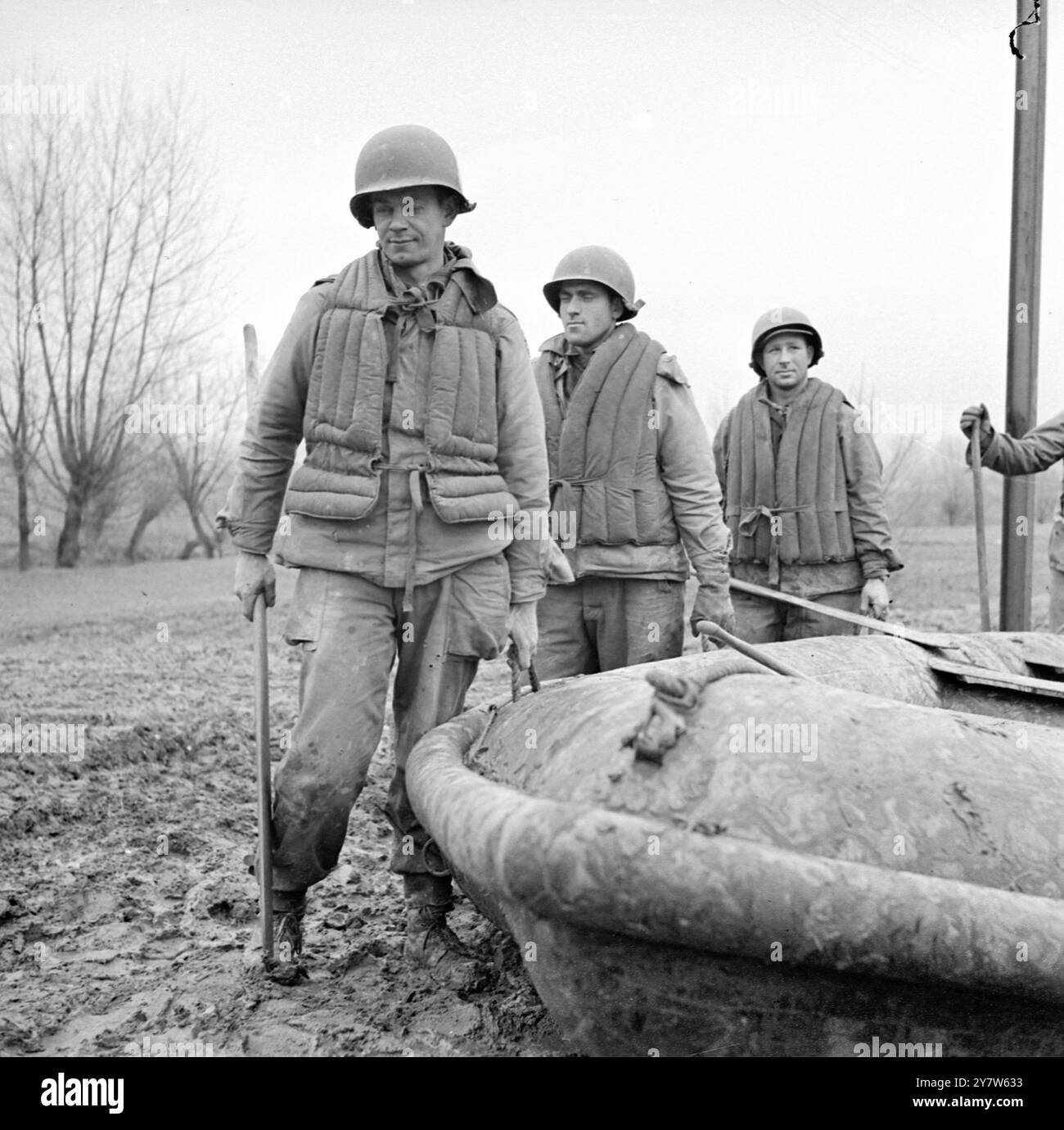 ALLIES INTENSIFY RIVER CROSSING EXERCISES WEST OF RHINE With British, Canadian and American forces overlooking the Rhine from Arnhem to Coblenz, and the bridgehead at Remagen growing every day, the Allies have intesified river crossing exercises west of Germany's last natural defence line on the Western Front.  Photo Shows:  Seventh Army troops rehearse a river crossing west of the Rhine, Left to Right, carrying their rubber assault dinghy, are Private First Class Osmus Leonard, of 322 Alameda Avenue, Astroia, Oregon, T/5 Elmore Scafibel, of Natalbany, Louisiana, and Sergeant George Prengress, Stock Photo