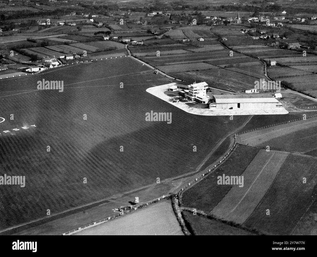 The Channel IslandsJersey's new £130,000 airport opened by bailiff's wife Constucted at a cost of £130,000 , the new airport at Jersey in the Channel Islands , was opened by Mrs Coutanche , wife of the Bailiff of Jersey .  One of the finest in the British Isles , the new aerodrome will enable nine services each way between Jersey, Southampton , London , Exeter and Brighton .  Nearly 700 passengers will be transported .  Photo shows:  An aerial view of the new Jersey airport showing the control buildings and landing field at the opening  ceremony . 10 March 1937 Stock Photo