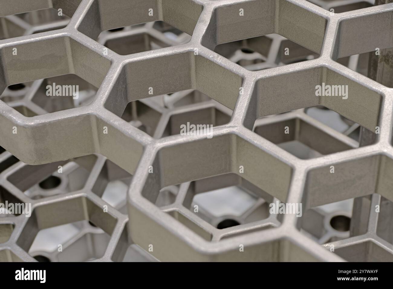 Openwork three-dimensional metal grid with hexagonal cells. Close up shot, abstract metalwork industry background. Stock Photo
