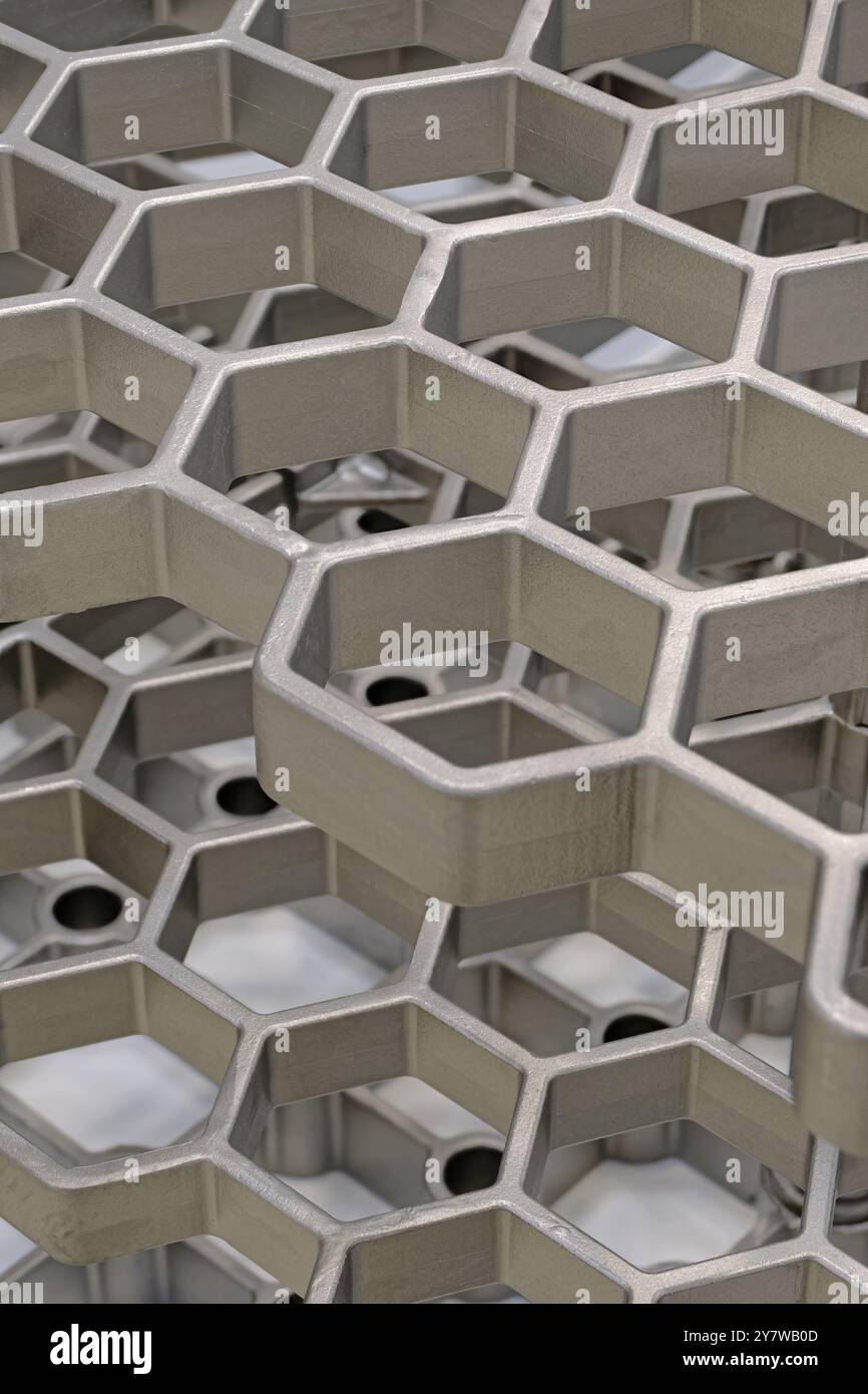 Openwork three-dimensional metal grid with hexagonal cells. Close up shot, abstract metalwork industry background. Stock Photo