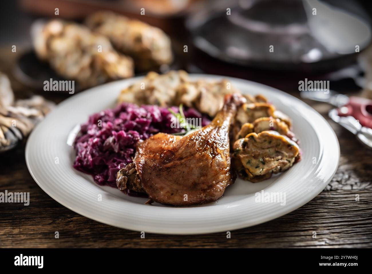 Portion of roast duck leg red cabbage homemade dumplings on plate and red wine on the background. Stock Photo