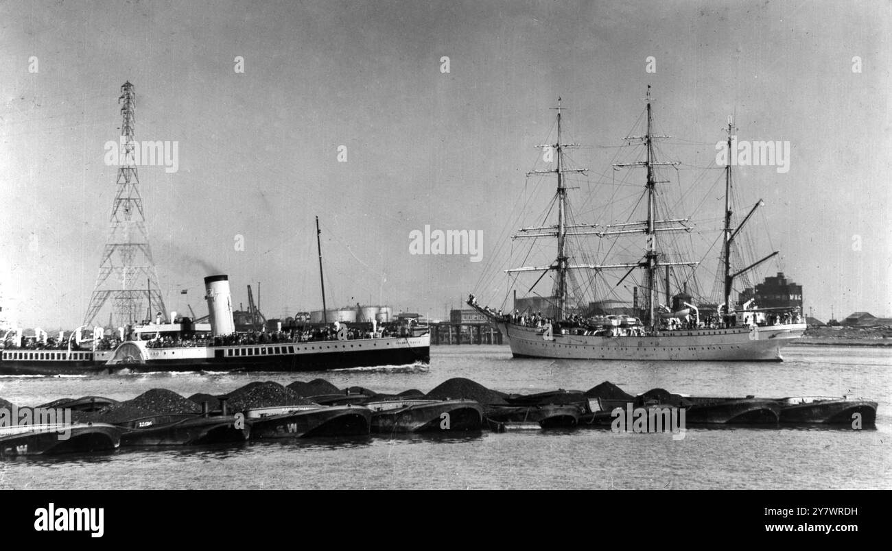 Golden Eagle steamship and sailing ship with electric pylon behind and coal heaps in front Stock Photo