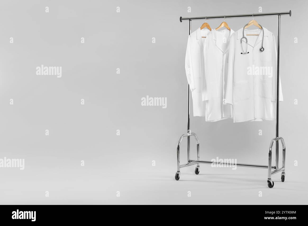 Doctor's coats with stethoscope on clothing rack against white ...